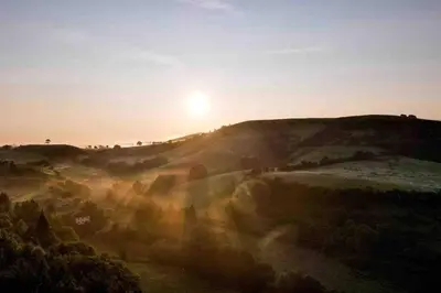 a sunset on a hill with the sun in the sky at The Shippen - Open-plan barn conversion, high-spec, stunning views in Norbury
