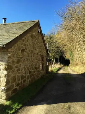 a stone building next to a dirt road with trees at The Shippen - Open-plan barn conversion, high-spec, stunning views in Norbury