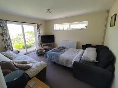 a bedroom with two beds and a couch and a window at Y Nyth in Newtown