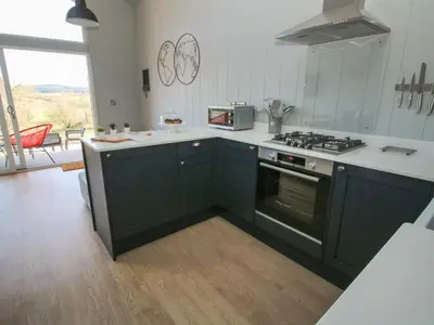 a kitchen with black cabinets and a stove top oven at Little Shelve Barn in Shrewsbury