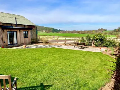 a house with a picnic table and a grass yard at Evenwood Byre in Kenley