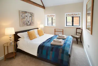 a bedroom with a large bed and a chair at Evenwood Byre in Kenley