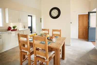 a kitchen and dining room with a wooden table and chairs at Evenwood Byre in Kenley
