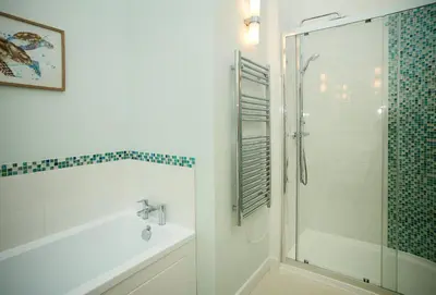 a bathroom with a shower and a tub and a sink at Evenwood Byre in Kenley