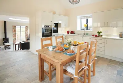 a kitchen with a wooden table with food on it at Evenwood Byre in Kenley