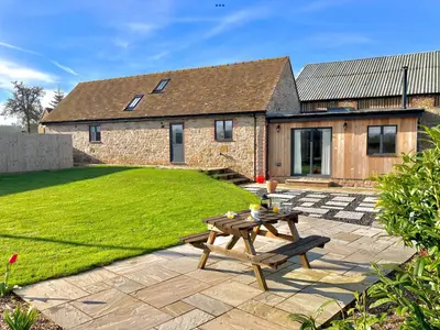 a backyard with a picnic table and a house at Evenwood Byre in Kenley