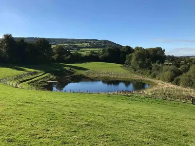 a green field with a pond in the middle at 3 Bed in Talybont-on-Usk oc-wal374 in Talybont