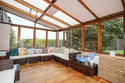 a conservatory with a couch in a room with windows at Gilfachwydd in Dolgellau
