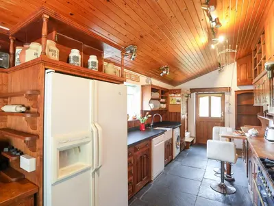 a kitchen with a white refrigerator and wooden ceilings at Gilfachwydd in Dolgellau