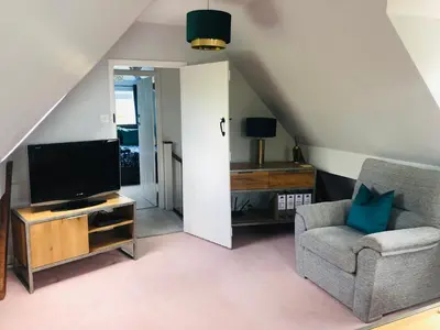a living room with a tv and a chair at The Annexe at Walnut Tree Cottage in Hope under Dinmore