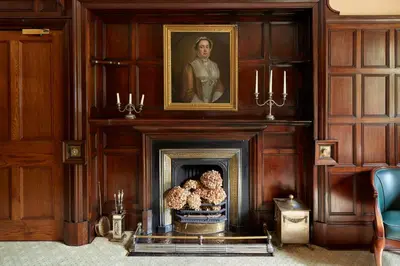 a room with a fireplace with a portrait of a man at Penmaenuchaf Hotel in Dolgellau
