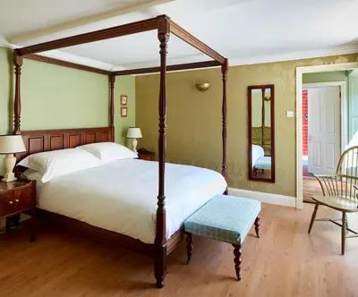 a bedroom with a large bed and a mirror at Penmaenuchaf Hotel in Dolgellau