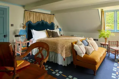 a bedroom with a bed and a chair at Penmaenuchaf Hotel in Dolgellau