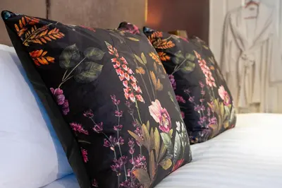 two black pillows with flowers on a bed at At Home Apartments in Shrewsbury