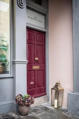 a red door on the side of a building with a plant at At Home Apartments in Shrewsbury