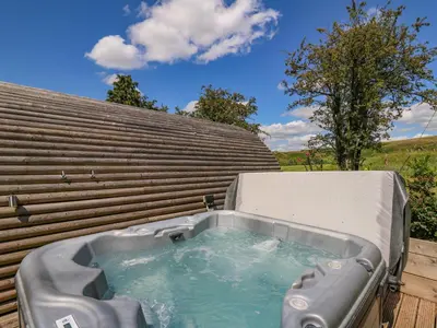 a hot tub sitting on the side of a building at Pine Lodge in Llangadog