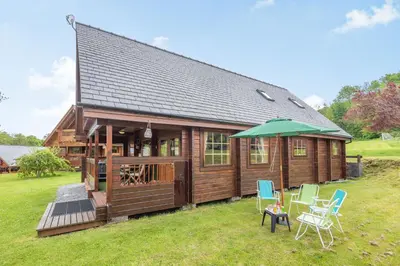a small house with chairs and an umbrella at Robin Lodge in Llanbedr