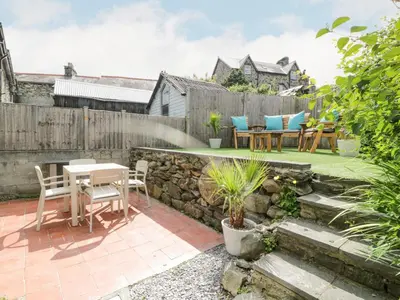 a patio with a table and chairs in a backyard at Y Bwthyn in Llanbedr