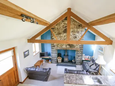 a view of a living room with a stone fireplace at Bodnant in Tywyn