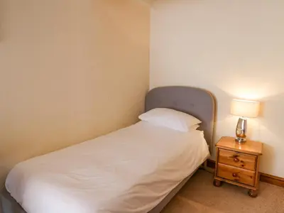 a bedroom with a bed and a night stand with a lamp at Bodnant in Tywyn