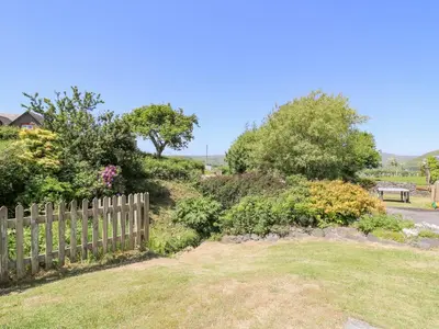 a wooden fence in a yard with flowers and a bench at Bodnant in Tywyn
