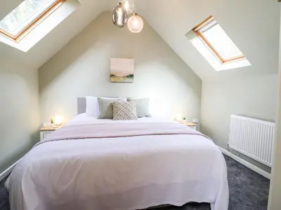 a bedroom with a large white bed with skylights at Ysgubor Craig Y Gronfa in Machynlleth