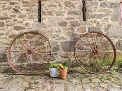 two large wooden wagon wheels next to a stone wall at Ysgubor Craig Y Gronfa in Machynlleth