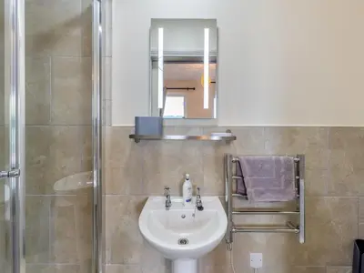 a bathroom with a sink and a shower with a mirror at The Stables in Forden