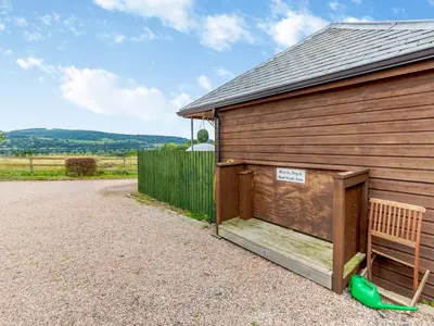 a wooden barn with a bench next to it at The Stables in Forden