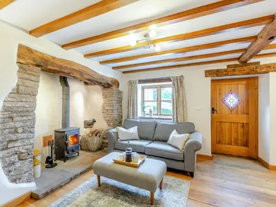 a living room with a couch and a stone fireplace at The Cider House in Clee Saint Margaret