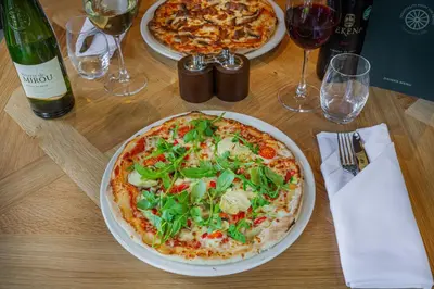 two pizzas on a wooden table with glasses of wine at The Wynnstay Hotel, Oswestry, Shropshire - The Coaching Inn Group in Oswestry