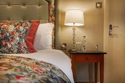 a bedroom with a bed and a lamp on a table at The Wynnstay Hotel, Oswestry, Shropshire - The Coaching Inn Group in Oswestry
