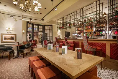 a restaurant with a large wooden table and chairs at The Wynnstay Hotel, Oswestry, Shropshire - The Coaching Inn Group in Oswestry