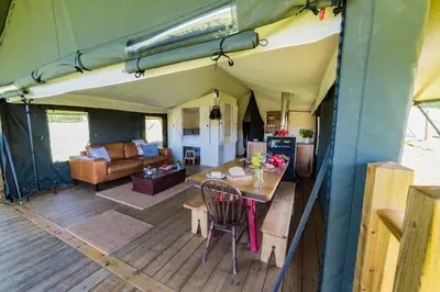 a living room with a table in a tent at Canvas & Campfires, Luxury Safari Tent Glamping, only Seren Tent has a hot tub in Lampeter