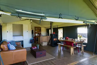 a living room with a tent with a couch and a table at Canvas & Campfires, Luxury Safari Tent Glamping, only Seren Tent has a hot tub in Lampeter