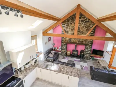 a kitchen and living room with a stone wall at Swn y Nant in Tywyn
