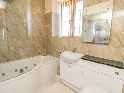 a bathroom with a sink and a bath tub and a mirror at Swn y Nant in Tywyn