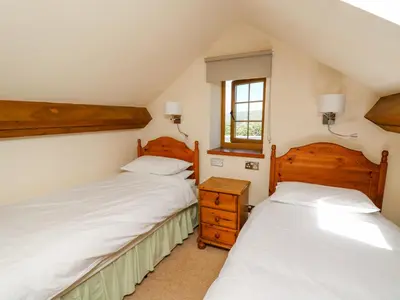 two beds in a small room with two windows at Swn y Nant in Tywyn