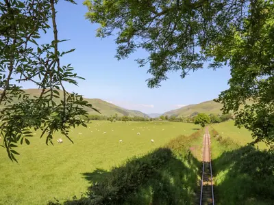 a field of sheep in a field with a train track at Swn y Nant in Tywyn