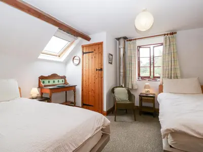 a bedroom with two beds and a desk and a window at Halls Mill in Kington