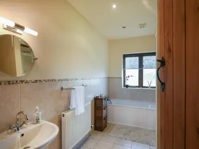 a bathroom with a sink and a tub and a mirror at Y Dderwen in Pen-y-bont-fawr