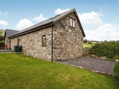 an old stone cottage with a grass yard at Y Dderwen in Pen-y-bont-fawr