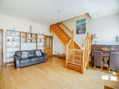 a living room with a couch and a staircase at Rockcliffe in Aberdyfi