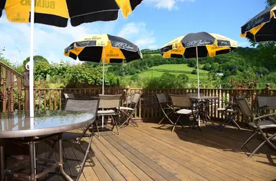 a deck with tables and chairs with umbrellas at The Mulberry Inn in Glyn-Ceiriog