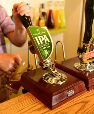 a man is pouring a bottle of beer into a machine at The Mulberry Inn in Glyn-Ceiriog