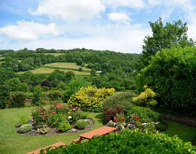 a bench in the middle of a garden with flowers at The Mulberry Inn in Glyn-Ceiriog