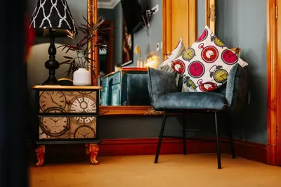 a chair sitting next to a side table with pillows at Boutique Shrewsbury Rooms in Shrewsbury