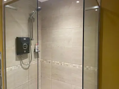 a shower with a glass door with a camera in it at Bear Cottage, Tyn Y Cwm in Scyborycoed