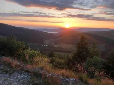 a sunset on a hill with the sun setting in the distance at Bear Cottage, Tyn Y Cwm in Scyborycoed