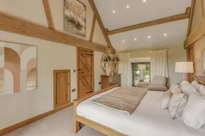 a bedroom with a large white bed and a chair at Hilltop View with Hot Tub in Brecon